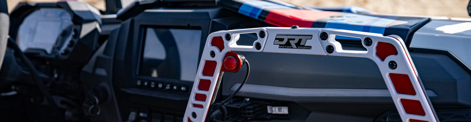 Rugged Radios Collection car‑harness push‑to‑talk button with red PTT, coiled cord, rugged connector, designed for steering‑wheel mounting in race vehicles